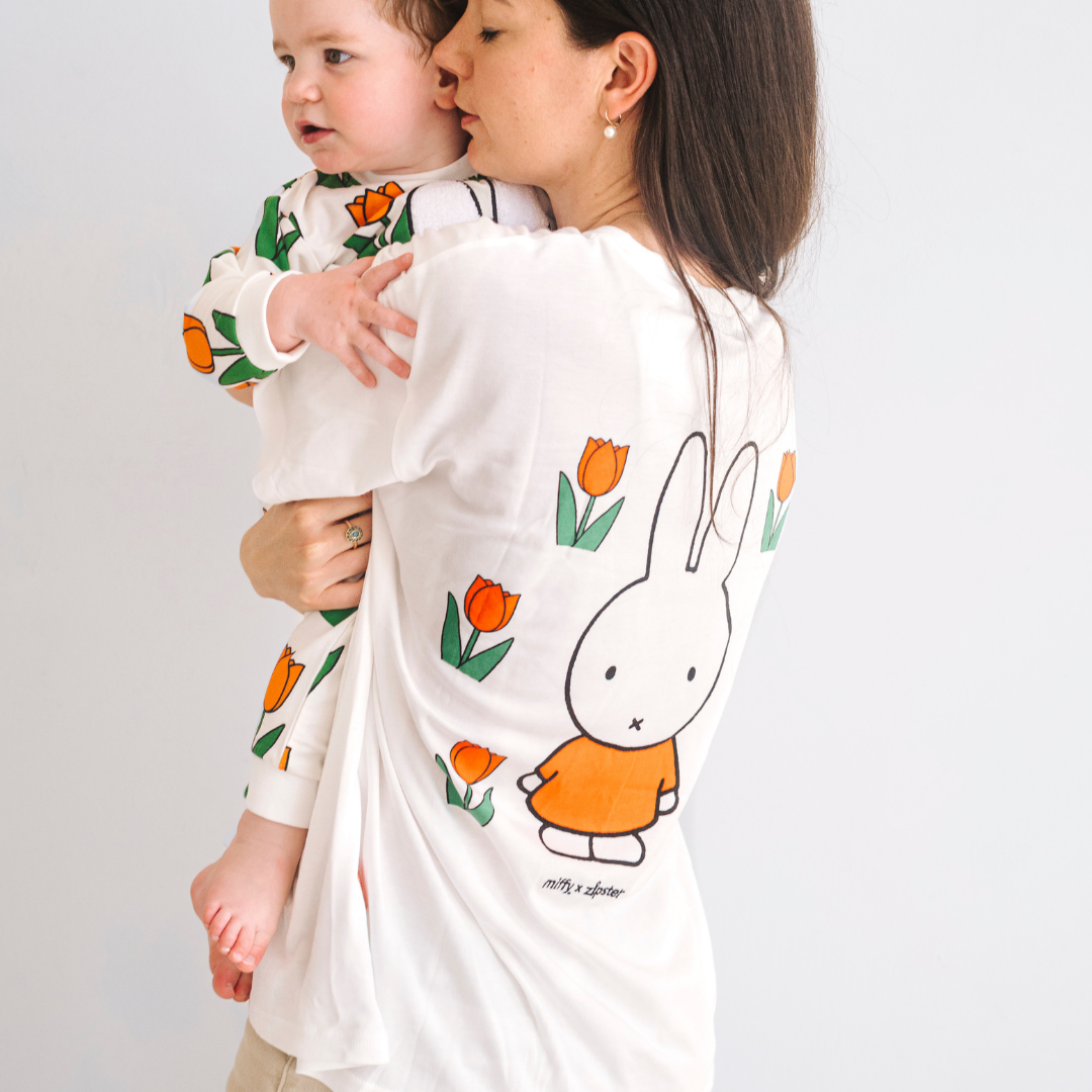 Donna che indossa la maglietta bianca per l'allattamento Miffy con un tulipano ricamato e cerniere per l'allattamento